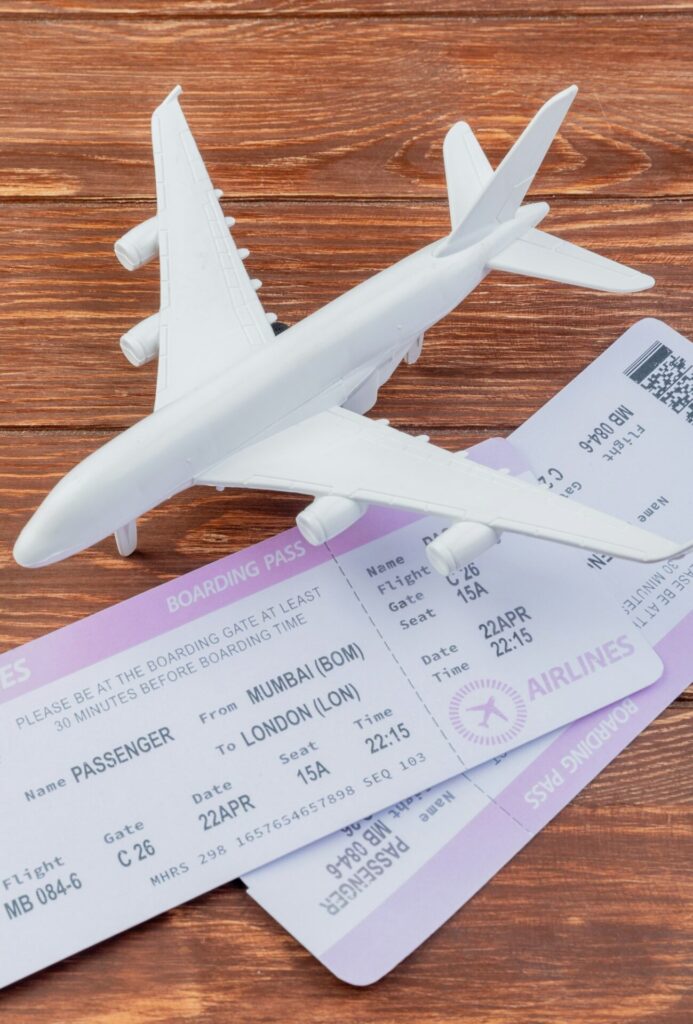 side view of white model airplane with plane tickets on a wooden background